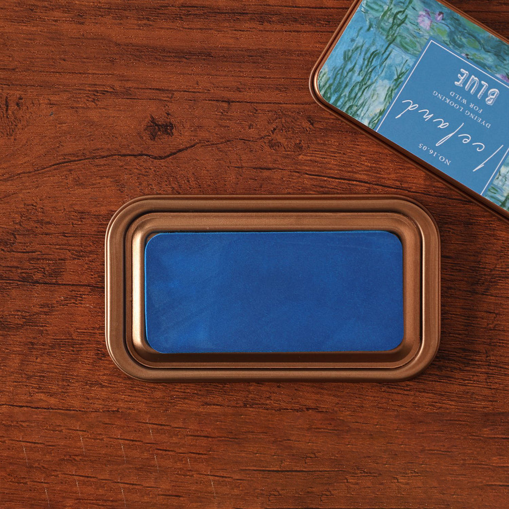 Vintage iron box ink pad in Iceland Blue open on wood, glacier blue lid beside