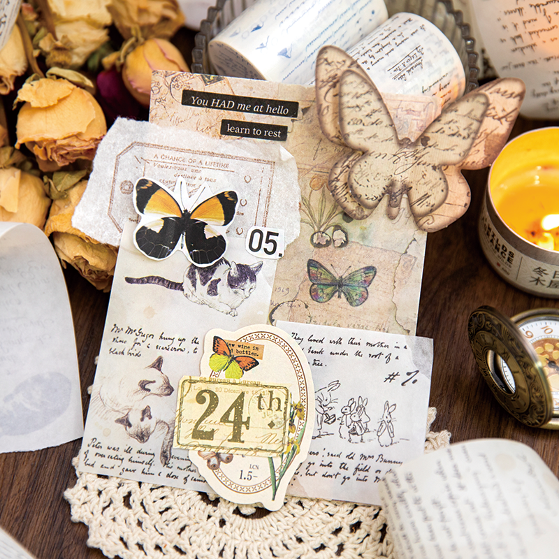 Junk journal collage spread with butterfly ephemera cat stickers vintage labels and lace doily on dark wood desk