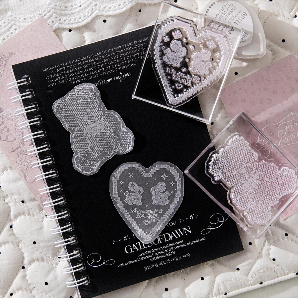 Bunny heart lace stamp impressions on black journal pages with scattered clear stamps