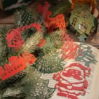 Red and green laser cut Christmas paper pieces with reindeer, trees and Santa on pine branches
