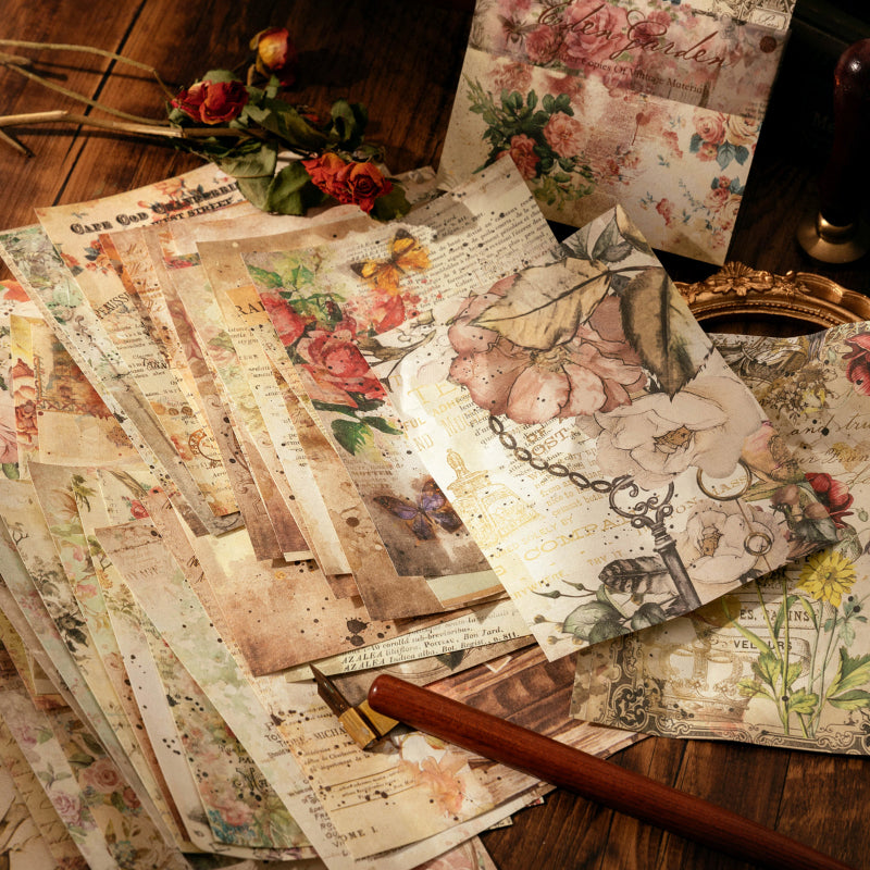 Scattered vintage collage paper sheets with botanical illustrations, butterflies, antique keys, and distressed script on a warm wooden background.
