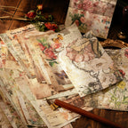 Scattered vintage collage paper sheets with botanical illustrations, butterflies, antique keys, and distressed script on a warm wooden background.