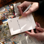 Hand writing on lined back of vintage postcard with fountain pen, showing mail-ready correspondence side and floral illustration front for pen pal letters
