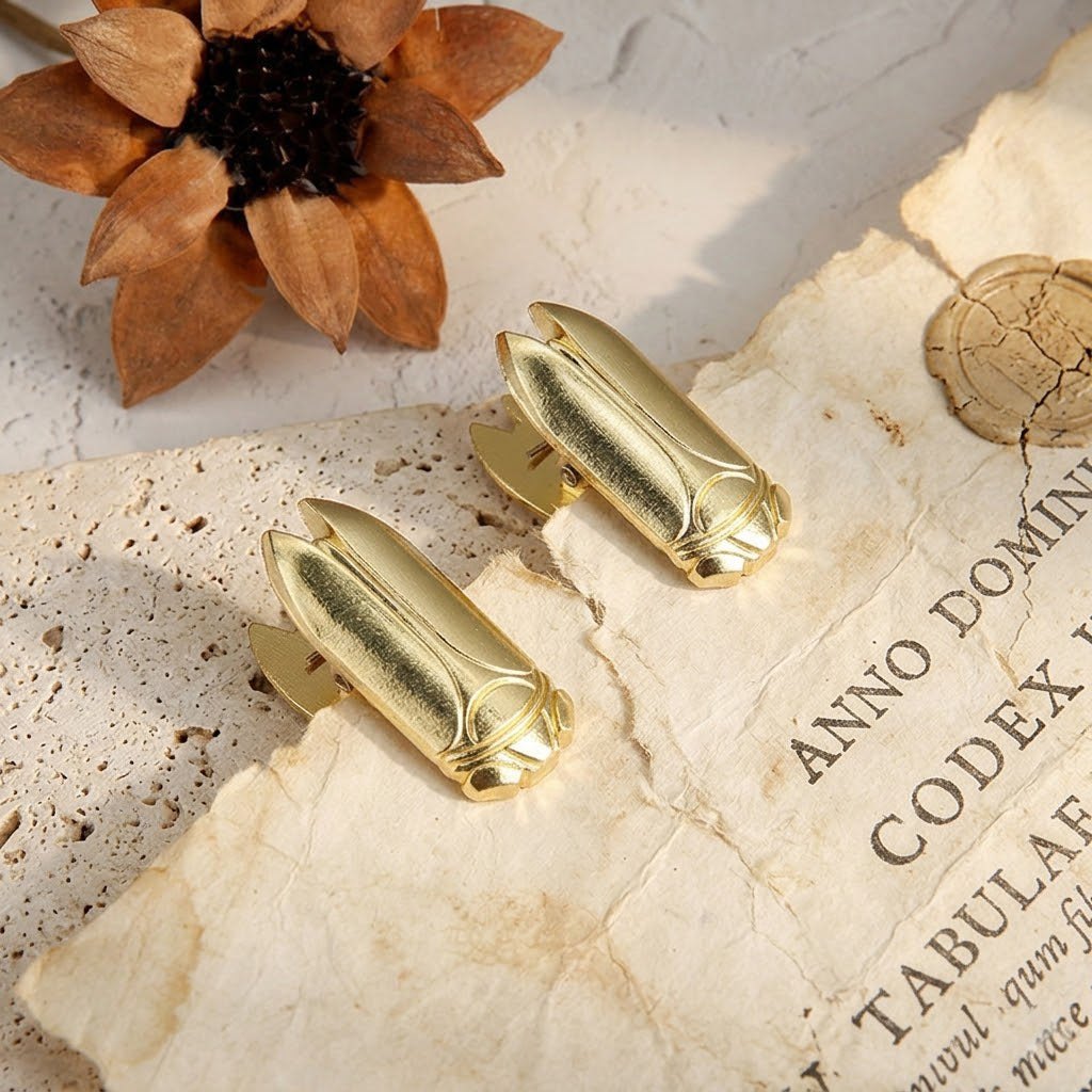 Set of 2 Luminous Gold vintage cicada metal binder clips holding aged French script paper. Ideal Dark Academia supplies for flat-lay photography.