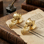 Set of 2 Luminous Gold vintage fox metal binder clips holding aged paper on a leather book. Ideal Cottagecore aesthetic supplies for junk journal spreads.