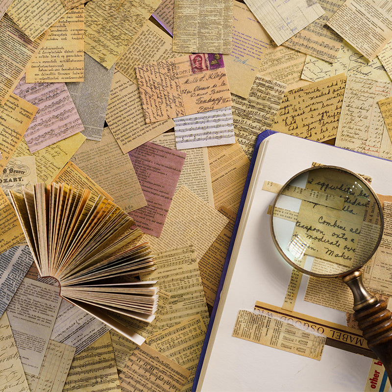 Mini paper booklet fanned beside a brass globe and magnifier