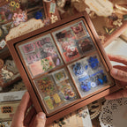 Image of hands holding multiple Mr.Paper Vintage Romantic Sticker Gift Boxes, sealed square boxes with window showing assorted vintage sticker designs inside
