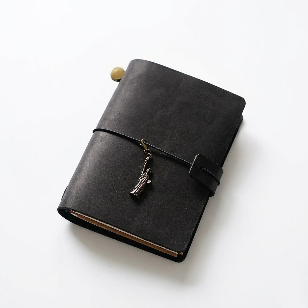 Obsidian Black passport size traveler's notebook in premium full-grain crazy horse leather with a vintage metal charm closure.