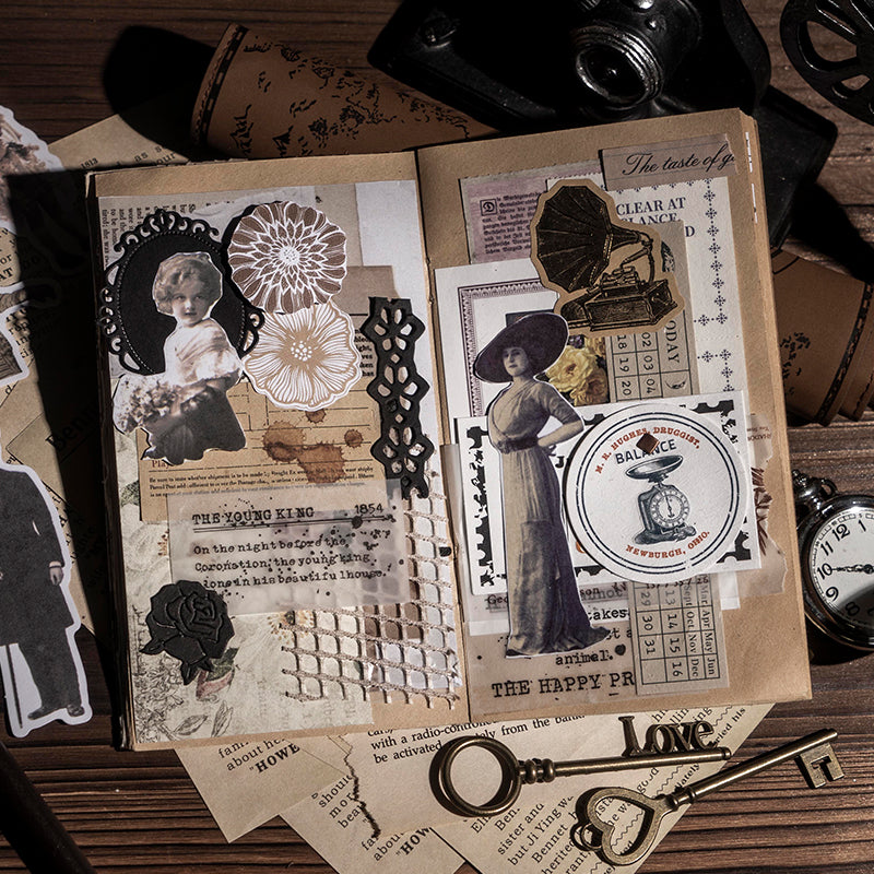 An open junk journal spread decorated with vintage character stickers, a black rose, mesh fabric, ephemera labels, and timeworn newspaper clippings on kraft paper.