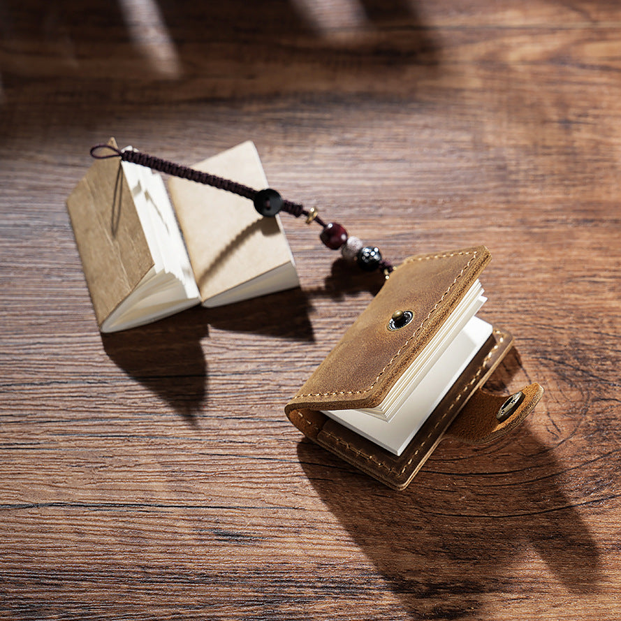 Two open mini leather notebooks showing tiny blank pages