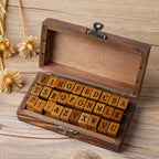 Open walnut wooden keepsake box showing alphabet letter stamps arranged in rows