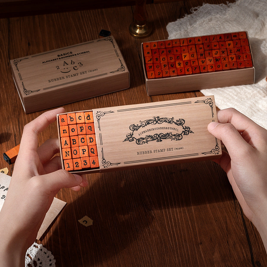 Hands opening a kraft box of vintage wooden alphabet stamps with rubber letter blocks inside