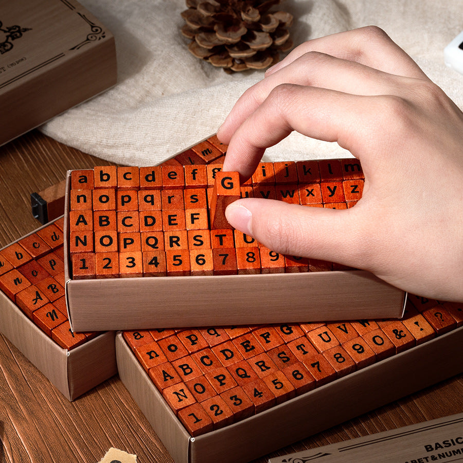 Hand picking a wooden letter stamp from the kraft storage box, orange rubber face