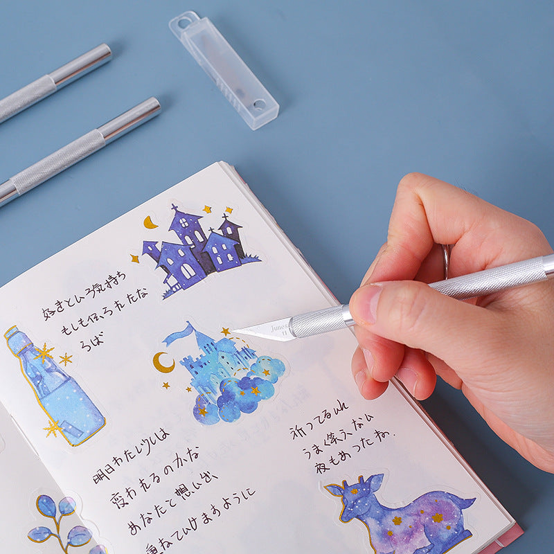Hand using a precision craft knife to cut details on a journal page