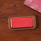 Vintage iron box ink pad in Sakura Pink open on wood, pink blossom lid beside