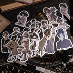 Loose vintage character stickers scattered across a black typewriter, featuring sepia-toned women and children in early 1900s attire with clean die-cut borders.