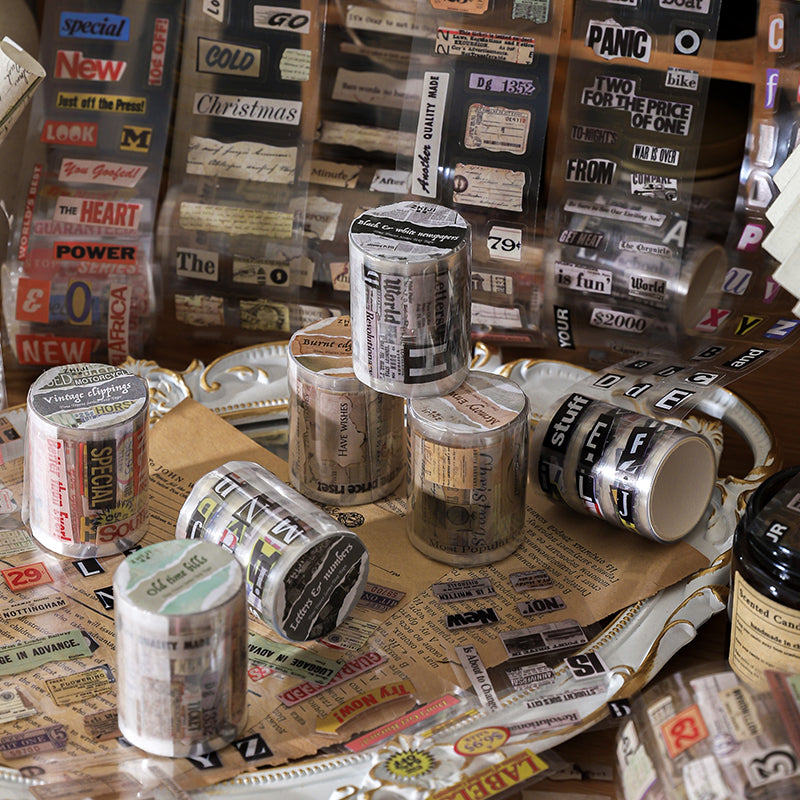 Six vintage ephemera PET tape rolls stacked on aged newspaper background showing newspaper headline and burnt edge diary designs