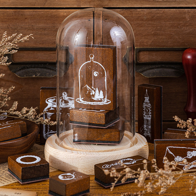 Wooden stamps arranged under a glass cloche on a vintage desk