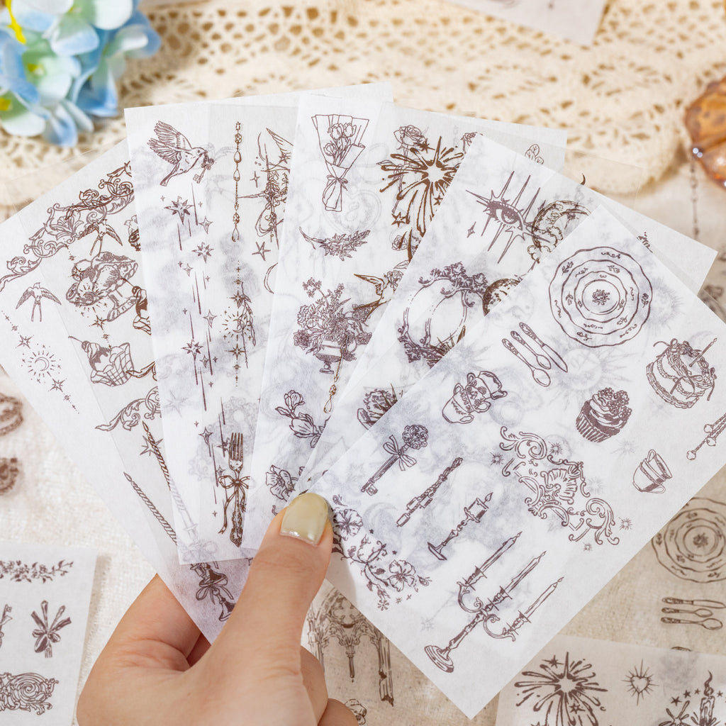Hand holding fanned sticker sheets with vintage ornamental designs