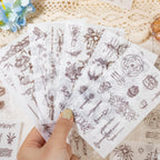 Hand holding fanned sticker sheets with vintage ornamental designs