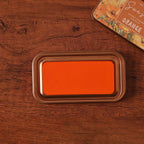 Vintage iron box ink pad in Sunset Orange open on wood, orange sunset lid beside