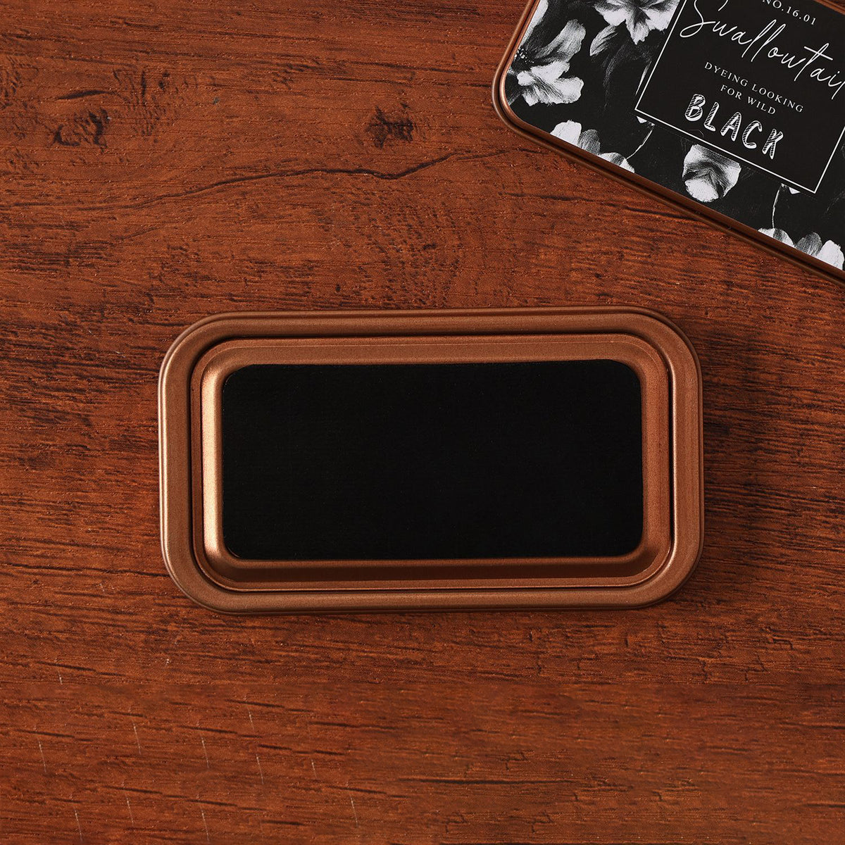Vintage iron box ink pad in Swallow Black open on wood, black swallow lid beside