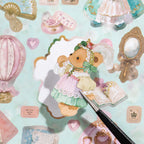 Close up of pink teddy bear sticker being placed with tweezers on pastel background