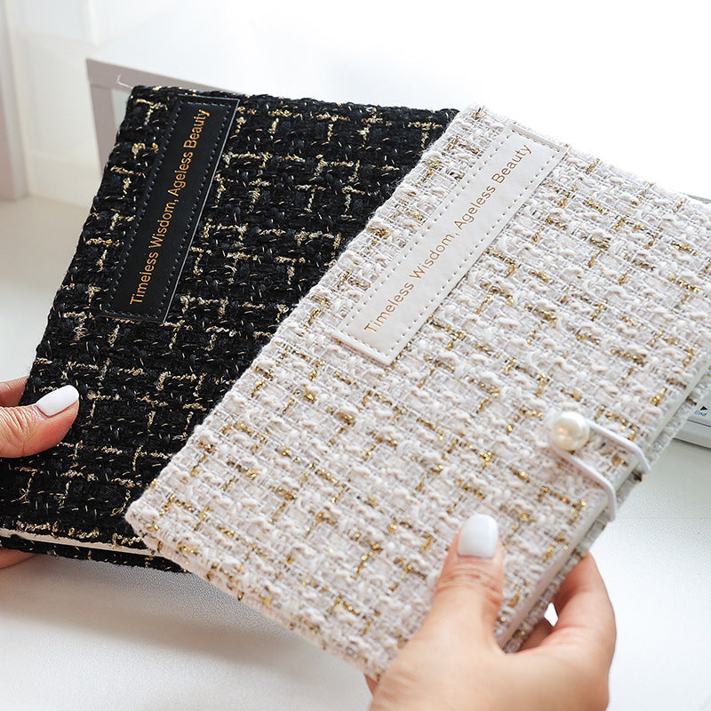 Hands holding black and white tweed fabric journals with pearl button closures