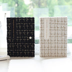 Black and white tweed journals standing side by side on a windowsill