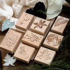 Vintage beech wood rubber stamps scattered on natural surface with carved botanical and butterfly designs, wooden base with detailed rubber surface for journaling