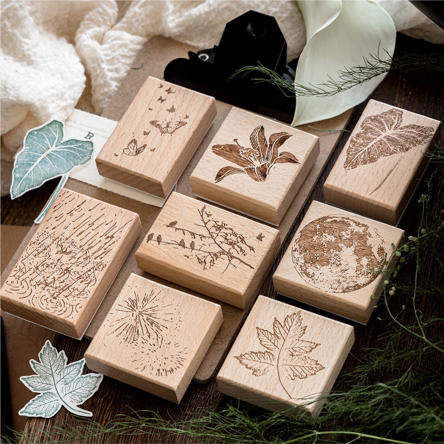 Vintage beech wood rubber stamps scattered on natural surface with carved botanical and butterfly designs, wooden base with detailed rubber surface for journaling