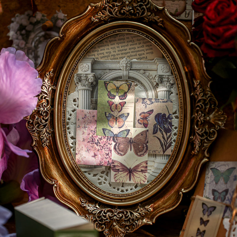 Vintage butterfly ephemera cards arranged in ornate frame with pink rose and iris prints on lightweight paper for dark academia journal decoration
