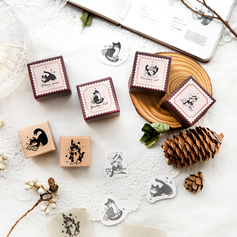 Set of six vintage cat wooden rubber stamps with beech handles on a white desk with pine cones and botanical accents, showing printed cat impressions for junk journaling
