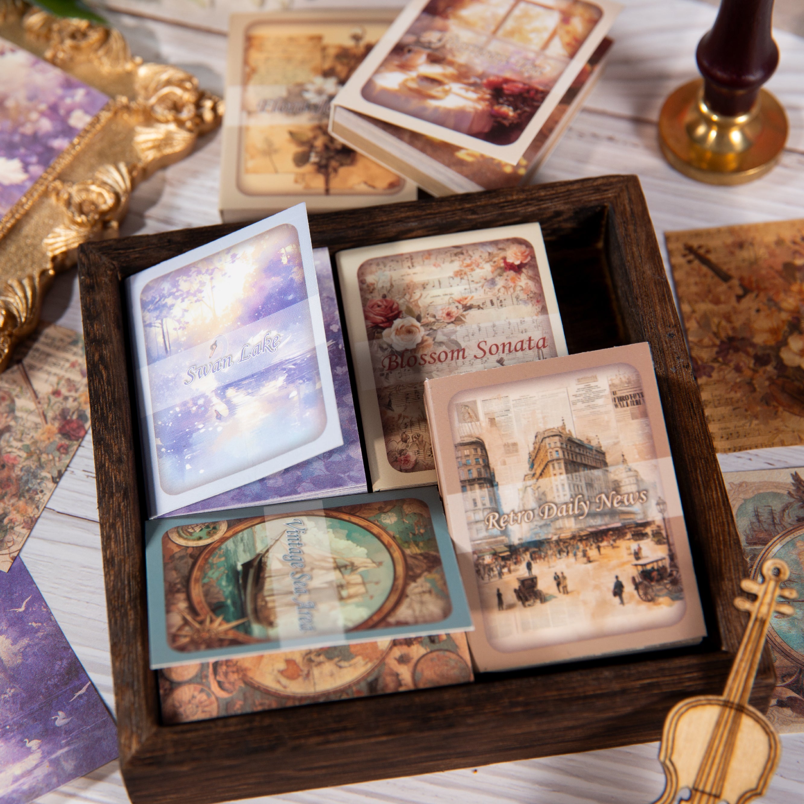 Six vintage ephemera card pads displayed with themed covers and round labels on a warm wooden background.