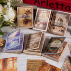 Scattered vintage ephemera cards with floral, swan, and nautical prints in assorted colors on a dark textured surface.