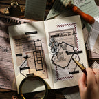 Open journal spread decorated with vintage letter stickers — travel log forms, typography labels and botanical frames layered over aged newsprint background