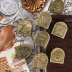 Eight vintage zinc alloy binder clips with embossed story designs on dark wood