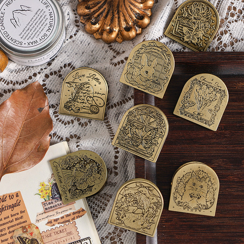 Eight vintage zinc alloy binder clips with embossed story designs on dark wood