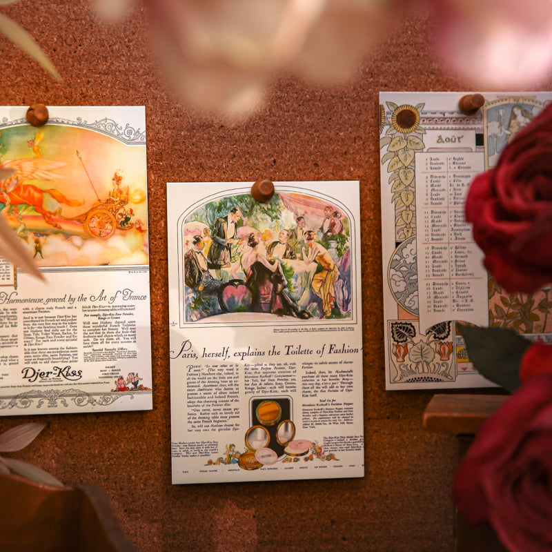 Three vintage illustration postcards on dark surface showing Paris fashion text, floral bouquet, and butterfly designs with gold decorative frames and lined back
