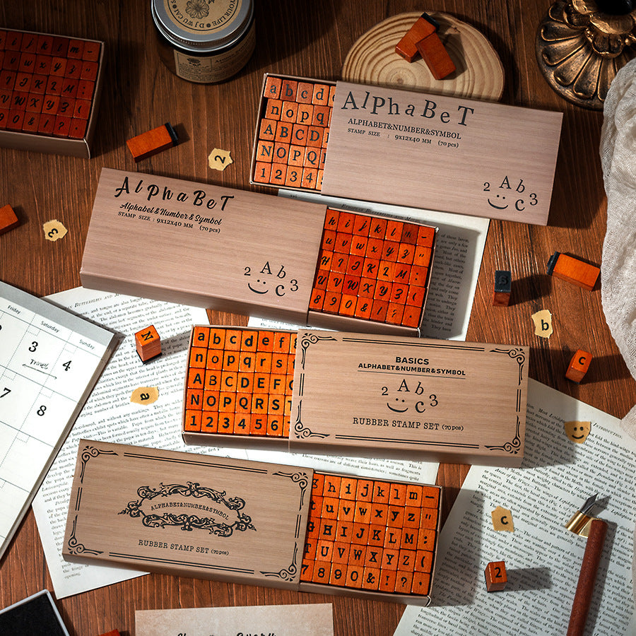 Vintage wooden alphabet stamp sets in kraft boxes with orange rubber letter blocks, four font styles flat lay on desk