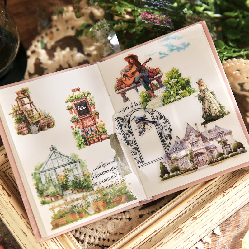 Open sticker booklet displaying vintage world stickers applied to pages, featuring greenhouse garden, guitar player, floral house, and manor house illustrations, journal ephemera in use