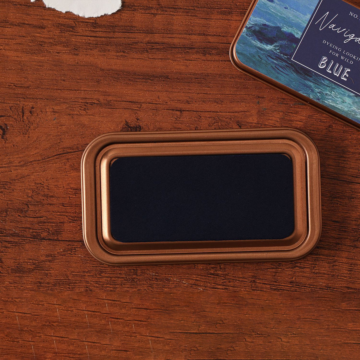 Vintage iron box ink pad in Voyage Blue open on wood, navy sea lid beside