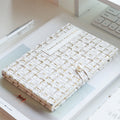 White tweed journal lying flat on a desk showing Timeless Wardrobe cover text