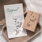 Vintage wooden stamp next to printed card with handwritten style text and butterfly trail ink impression, journal ephemera and stationery craft display