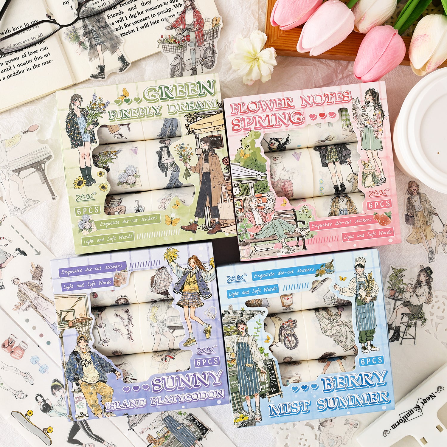 Overhead shot of all four styles of the Radiance Gentle Words washi tape collection: Meadow Whispers (Green), Sunny Campus (Purple), Spring Picnic (Pink), and Cozy Café (Blue). Each set contains 6 rolls.