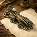 An aged antique bronze Victorian Lady's Hand metal journal clip clamping a rolled section of paper on calligraphic script. Softly lit vintage style.