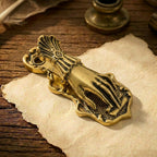 An aged antique gold Victorian Lady's Hand metal journal clip clamping a rolled section of paper on calligraphic script. Softly lit vintage Dark Academia style.script. Softly lit vintage Dark Academia style.