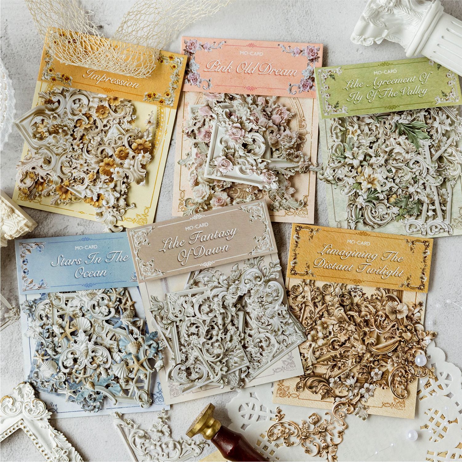 Aesthetic flat lay showcasing all six packs of the vintage 3D relief corner frame ephemera collection. The laser-cut paper packs are beautifully arranged with delicate lace, pearls, and a vintage wax seal stamp.
