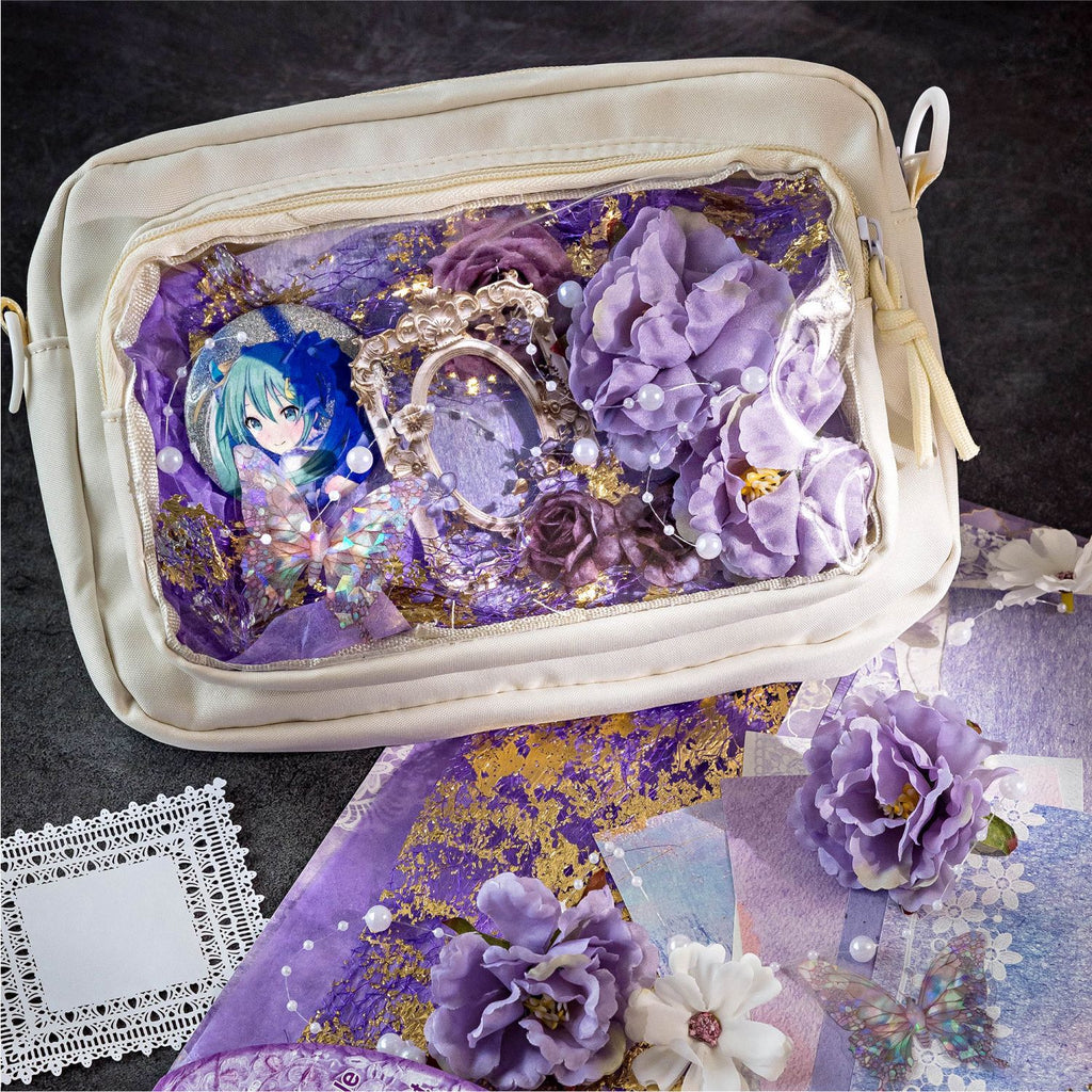 Creative Ita bag decoration using the Amethyst Twilight mixed media kit. The clear window displays an anime character pin beautifully framed with 3D purple flowers, holographic butterflies, gold foil paper, and purple mesh.