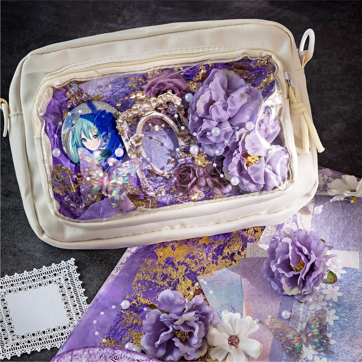 Creative Ita bag decoration using the Amethyst Twilight mixed media kit. The clear window displays an anime character pin beautifully framed with 3D purple flowers, holographic butterflies, gold foil paper, and purple mesh.